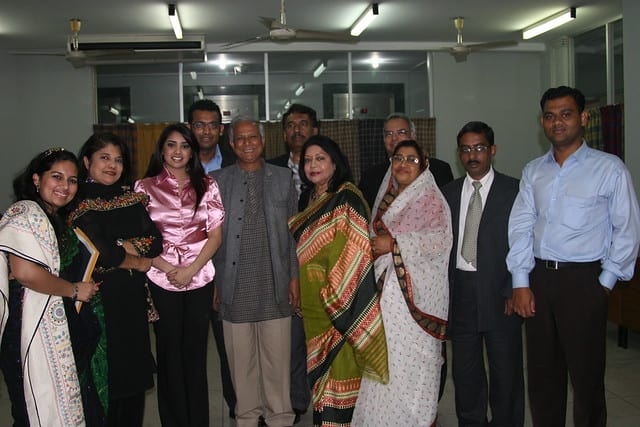 A colour photograph: eleven adults standing together indoors for a group portrait