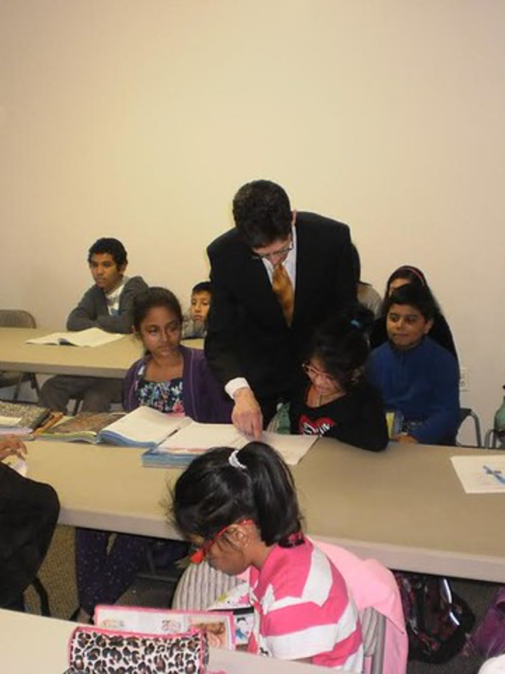 A mentor helping students with schoolwork in a classroom