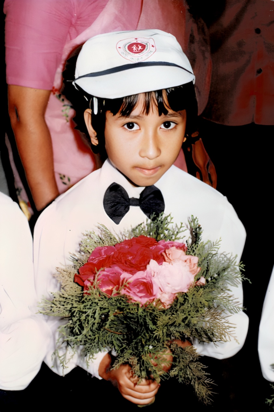Child in uniform holding a bouquet at a program ceremony